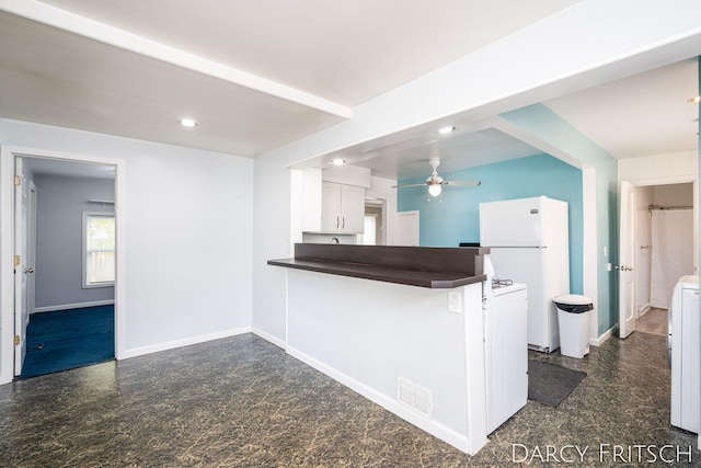 kitchen with dark countertops, visible vents, baseboards, freestanding refrigerator, and white cabinets