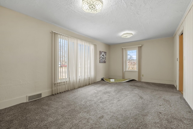 empty room featuring carpet flooring, visible vents, and a textured ceiling