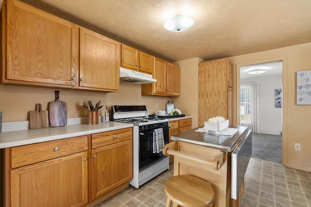 kitchen with under cabinet range hood, light colored carpet, light countertops, range with gas stovetop, and a textured ceiling