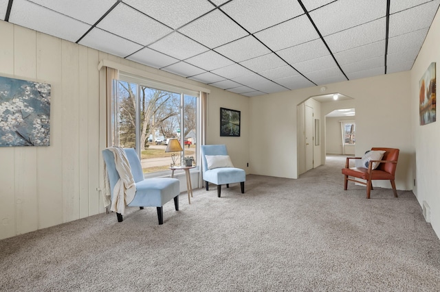 sitting room with arched walkways, light colored carpet, and a paneled ceiling