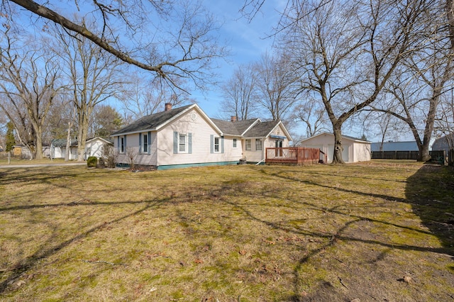 view of front of home featuring a front yard, an outbuilding, a shed, a chimney, and a deck