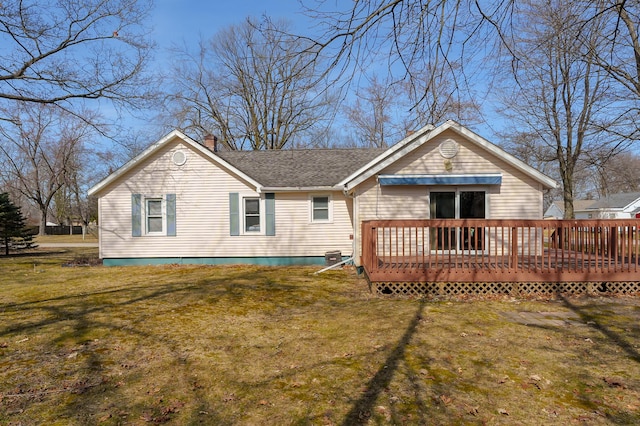 rear view of house featuring a deck, a chimney, a yard, and a shingled roof