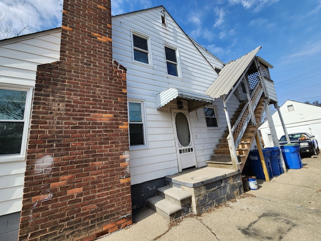 back of house featuring a chimney and metal roof