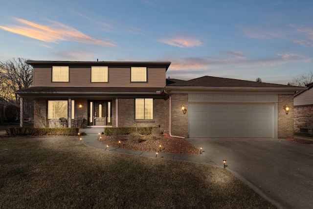 traditional home with brick siding, a porch, an attached garage, and driveway