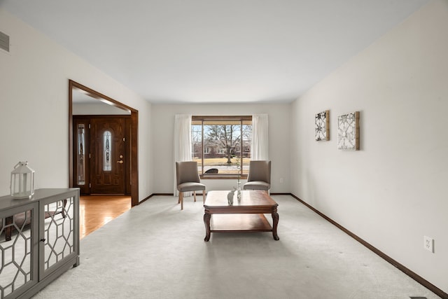 living area featuring visible vents, baseboards, and light carpet