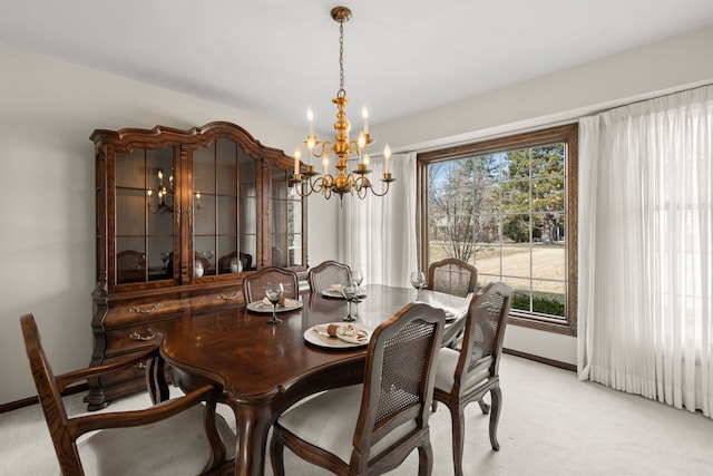 dining room featuring light colored carpet, baseboards, and a chandelier