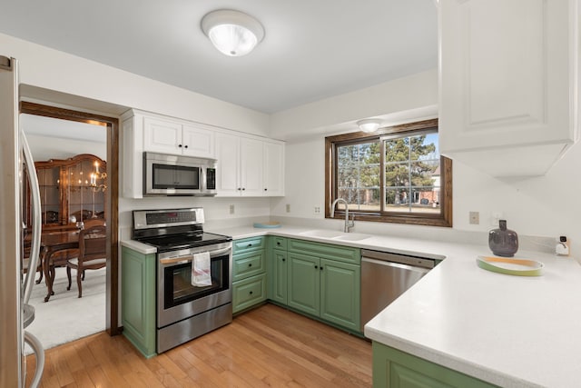 kitchen featuring white cabinets, stainless steel appliances, green cabinets, and a sink