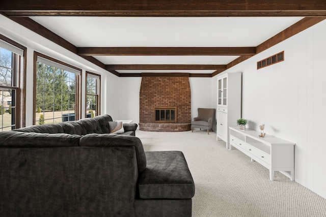 living area with light colored carpet, beamed ceiling, a fireplace, and visible vents