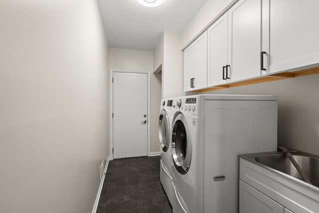 washroom with baseboards, dark tile patterned flooring, cabinet space, a sink, and washer and clothes dryer