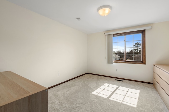 unfurnished room with baseboards, visible vents, and light carpet