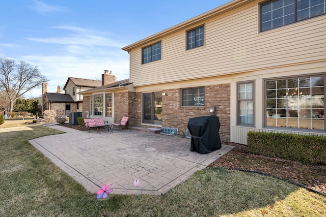 back of house with cooling unit, brick siding, a lawn, and a patio area