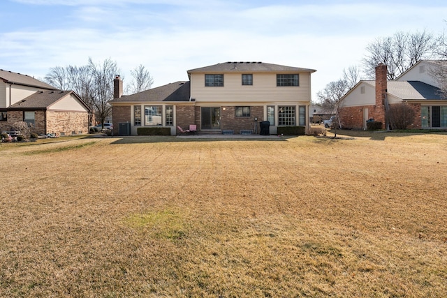 rear view of house with a yard, central air condition unit, brick siding, and a patio area