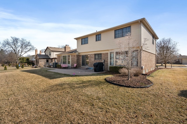 rear view of house featuring a patio area, brick siding, and a lawn