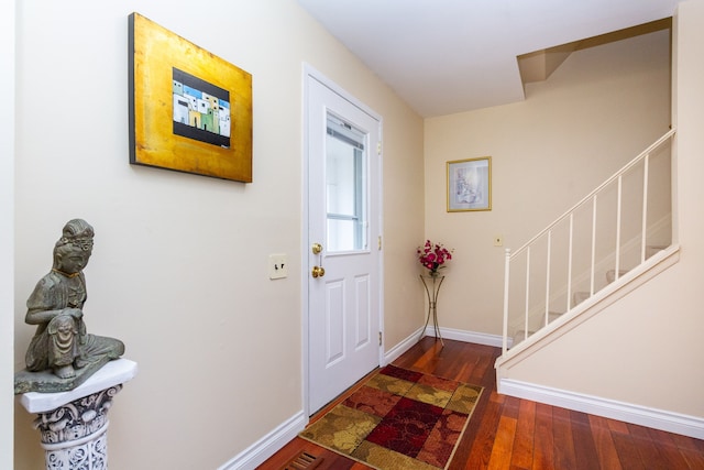 foyer featuring baseboards, dark wood-type flooring, and stairs