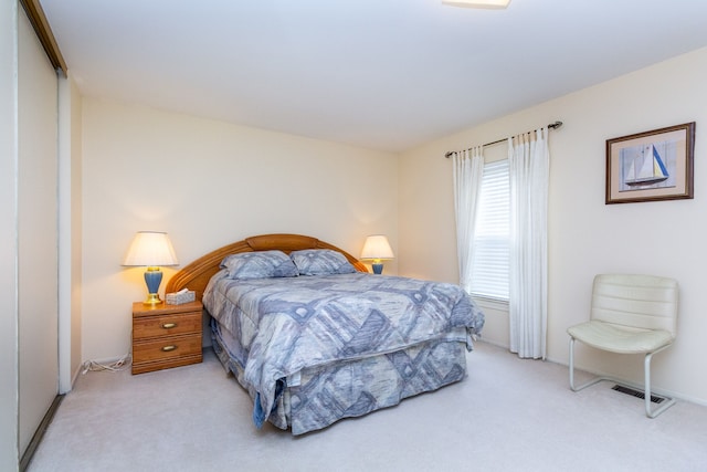 bedroom featuring baseboards, visible vents, and light carpet