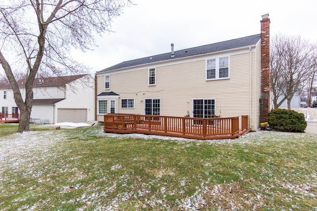 back of house featuring a detached garage, a chimney, a deck, a yard, and an outdoor structure