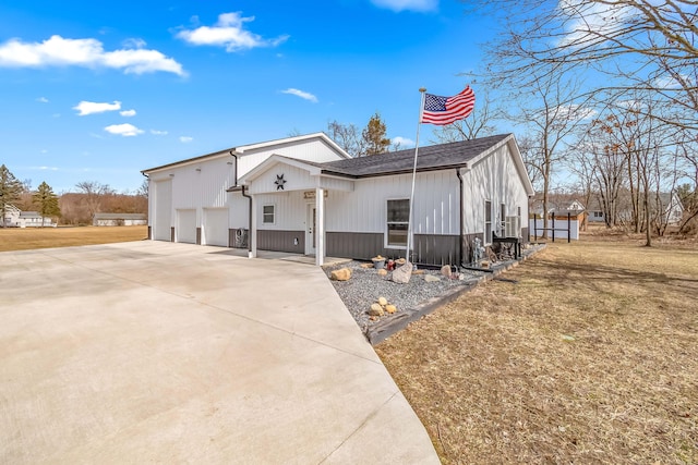 view of front facade featuring concrete driveway, a garage, a front yard, and a shingled roof