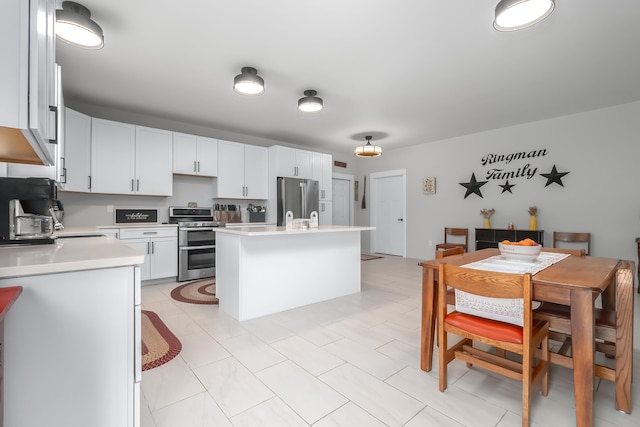 kitchen featuring white cabinetry, appliances with stainless steel finishes, a center island with sink, and light countertops