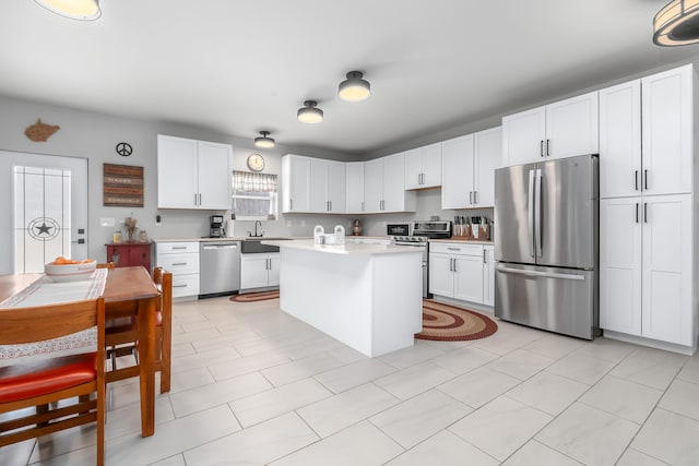 kitchen featuring light countertops, white cabinets, a center island, and stainless steel appliances