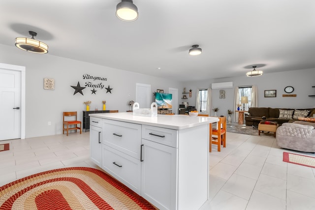 kitchen featuring light tile patterned floors, light countertops, white cabinets, a wall mounted air conditioner, and open floor plan