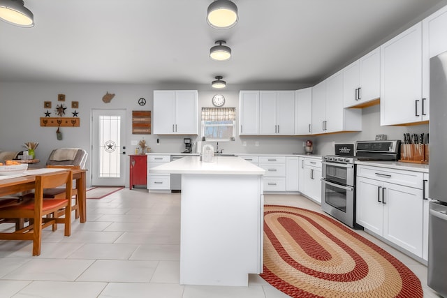 kitchen with light tile patterned floors, range with two ovens, light countertops, white cabinets, and a center island