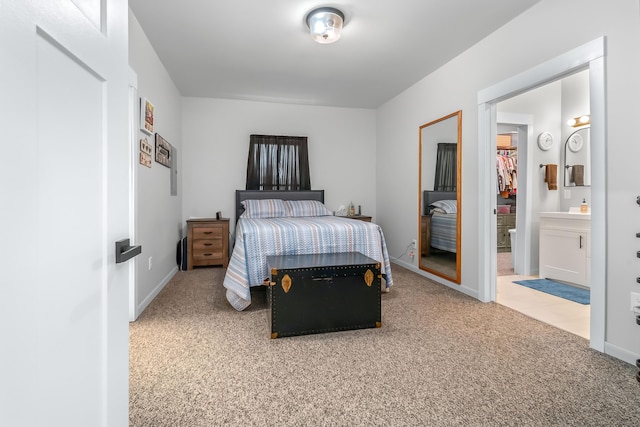 carpeted bedroom featuring ensuite bath, a spacious closet, baseboards, and a closet