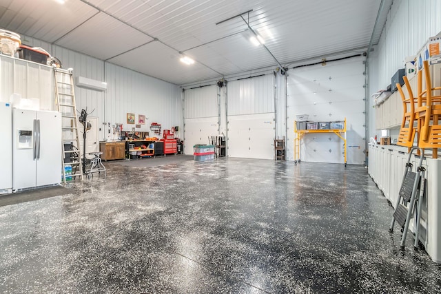 garage featuring a workshop area, white refrigerator with ice dispenser, and metal wall