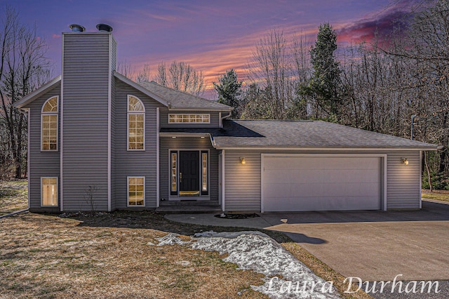 view of front of house featuring a shingled roof, an attached garage, a chimney, and concrete driveway