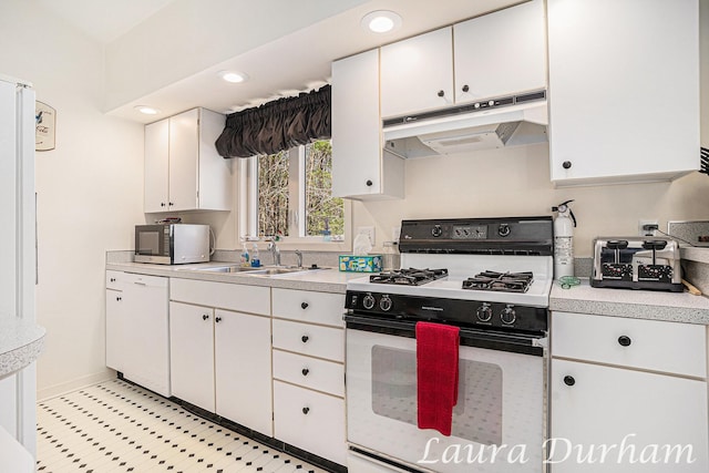 kitchen featuring white dishwasher, light countertops, gas range oven, under cabinet range hood, and white cabinetry