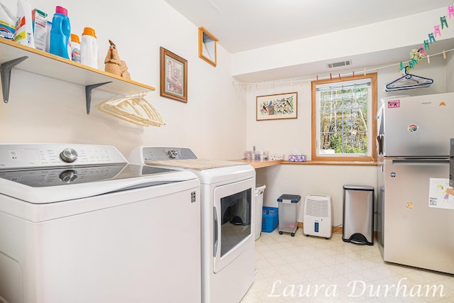 clothes washing area with laundry area, independent washer and dryer, visible vents, and light floors