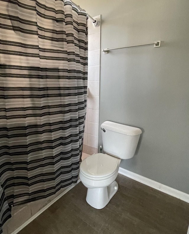 full bathroom featuring a shower with shower curtain, toilet, wood finished floors, and baseboards