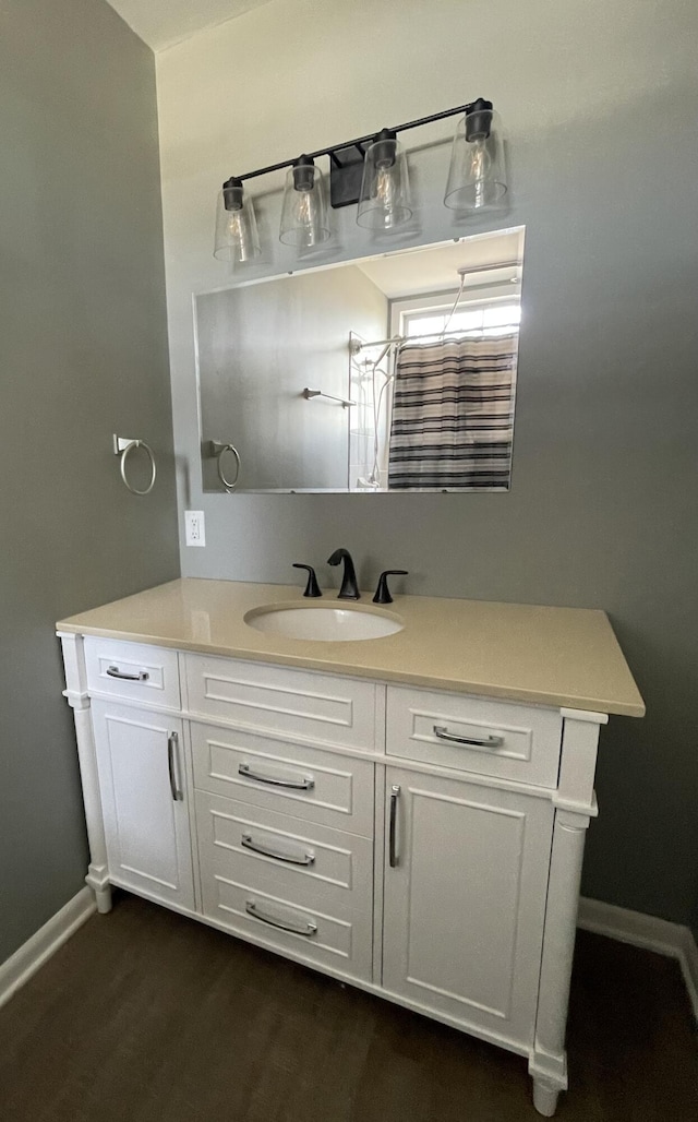 bathroom with vanity, wood finished floors, and baseboards