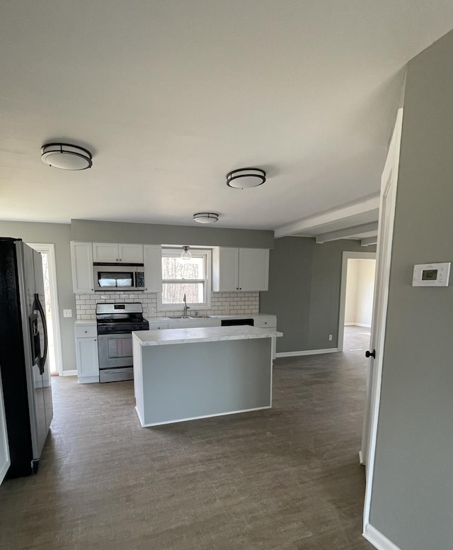 kitchen with a sink, backsplash, a center island, appliances with stainless steel finishes, and dark wood-style flooring