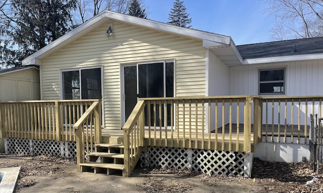 rear view of house featuring a shingled roof and a deck