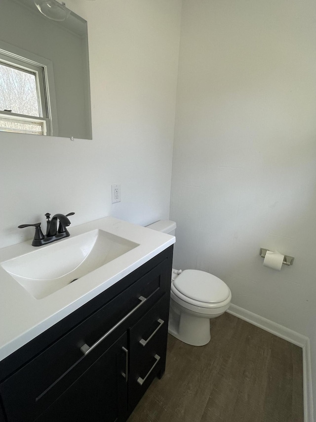 bathroom with toilet, vanity, and wood finished floors