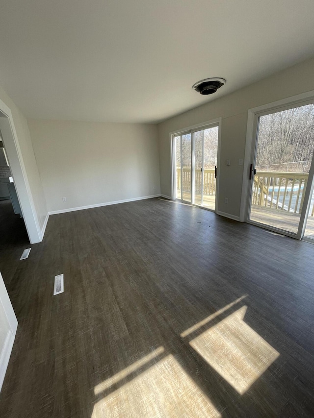 unfurnished living room featuring baseboards and dark wood-style floors