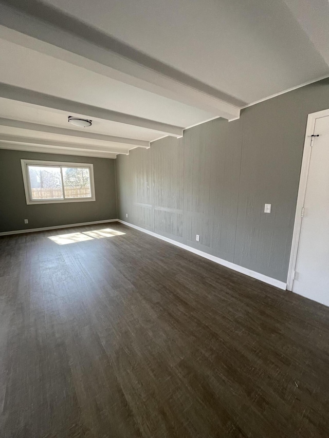 empty room with beamed ceiling, wood finished floors, and baseboards