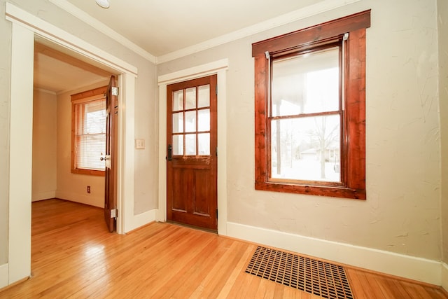 doorway to outside with crown molding, light wood-style floors, visible vents, and baseboards