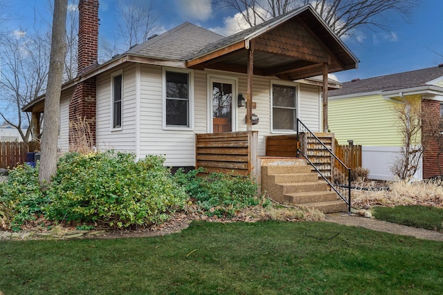 bungalow with a chimney, fence, a front yard, and roof with shingles