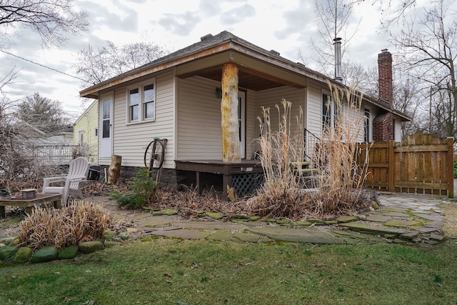 back of property with a chimney and fence