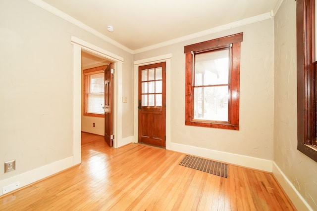 foyer entrance featuring light wood finished floors, visible vents, baseboards, and ornamental molding