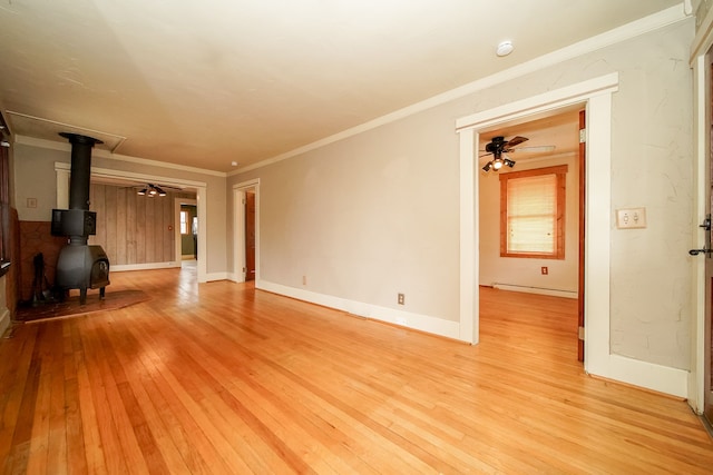 unfurnished living room featuring a baseboard radiator, ceiling fan, a wood stove, and light wood finished floors