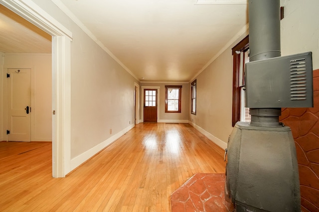 foyer with crown molding, a wood stove, baseboards, and light wood finished floors