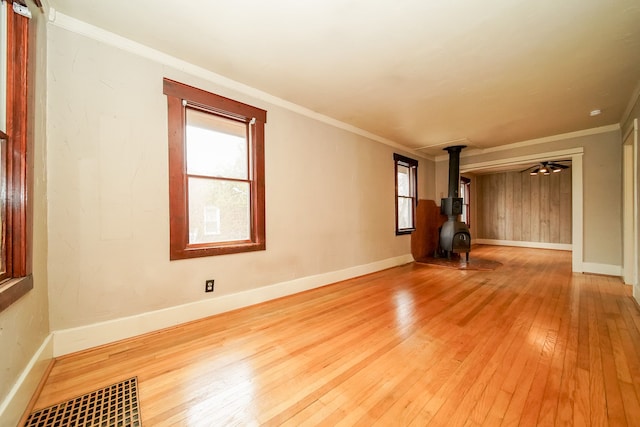 spare room with visible vents, ornamental molding, a wood stove, and hardwood / wood-style flooring