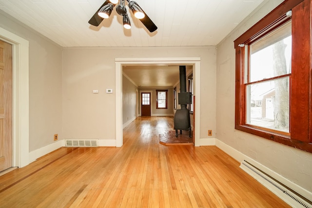 unfurnished room with light wood-type flooring, visible vents, a ceiling fan, baseboards, and baseboard heating