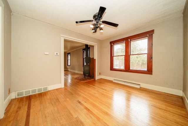 unfurnished room featuring visible vents, light wood-style flooring, a baseboard heating unit, and baseboards