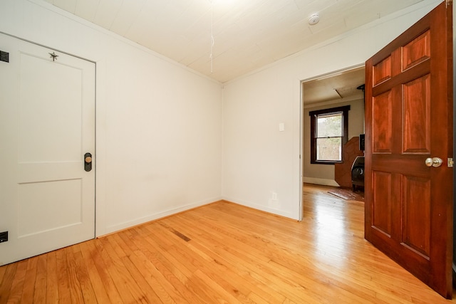 empty room with visible vents, light wood-style flooring, crown molding, and baseboards