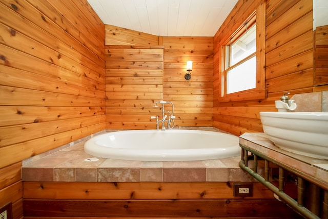 bathroom with a sink, a bath, and wood walls