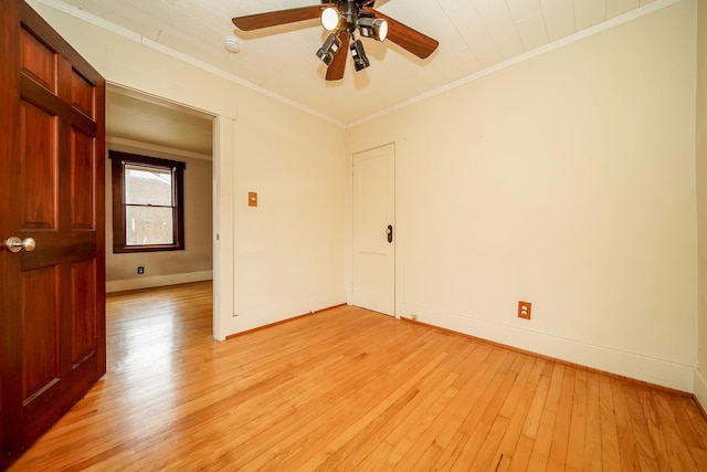 unfurnished room with crown molding, light wood-style flooring, and baseboards