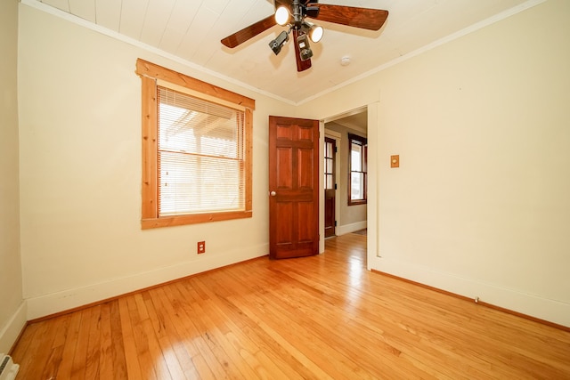 spare room featuring a healthy amount of sunlight, baseboards, light wood-style floors, and ornamental molding